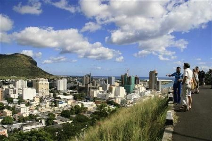 A tour guide stands with a group of tourists at a viewpoint overlooking Port Louis