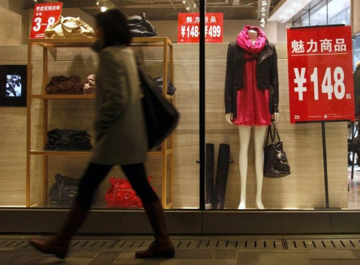 A shopper walks past a window displaying prices of dresses and handbags at a shopping mall in central Beijing
