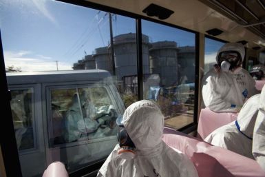 Officials from the Tokyo Electric Power Co. and journalists look out from bus windows as workers pass by in a van inside the grounds of the crippled Fukushima Daiichi nuclear power plant