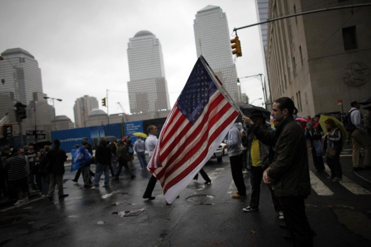 A man holds a U.S. flag while others pause for a moment of silence to pay their respects at the site of the former Twin Towers in New York