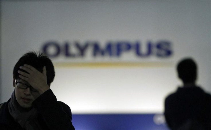 Men walk past a sign of Olympus Corp outside the company's showroom in Tokyo