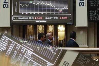 People walk past screens at the bourse in Madrid