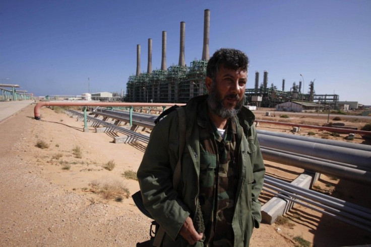 An armed National Transitional Council fighter patrols inside the Libyan Oil Refining Company in Ras Lanuf