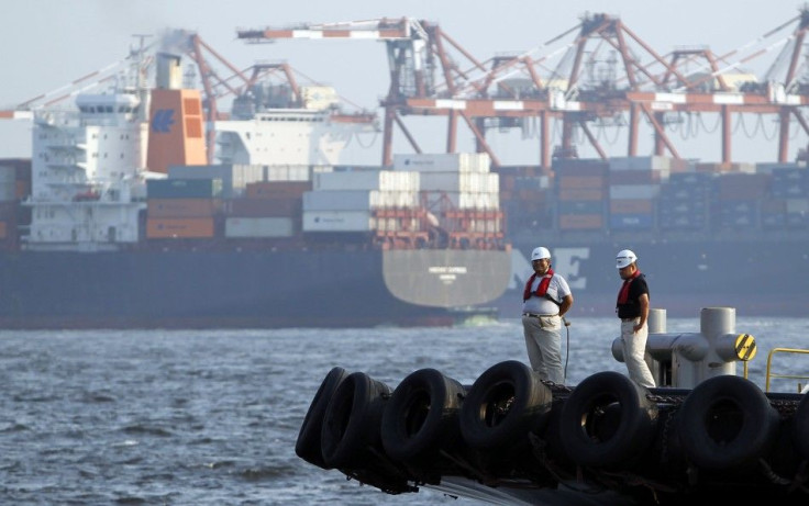 Workers stand on a ship in front of cargo ships at a port in Tokyo