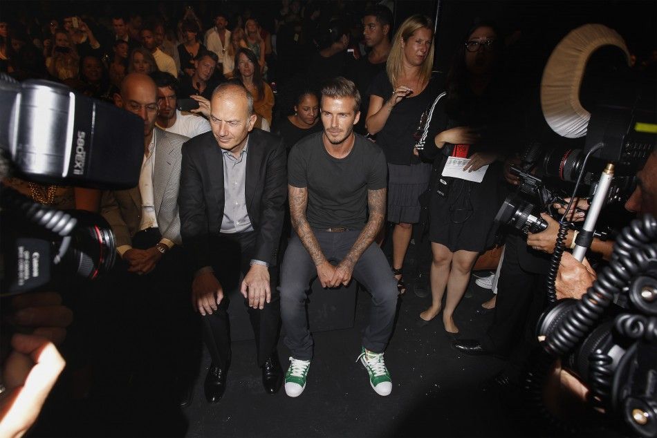 Soccer star David Beckham R sits with Adidas executive Erich Stamminger C before a presentation of the Y-3 SpringSummer 2013 collection during a walk through at New York Fashion Week September 9, 2012.