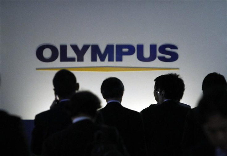 People walk past a sign of Olympus Corp outside the company's showroom in Tokyo