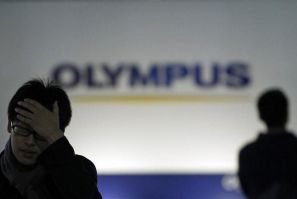 Men walk past a sign of Olympus Corp outside the company&#039;s showroom in Tokyo