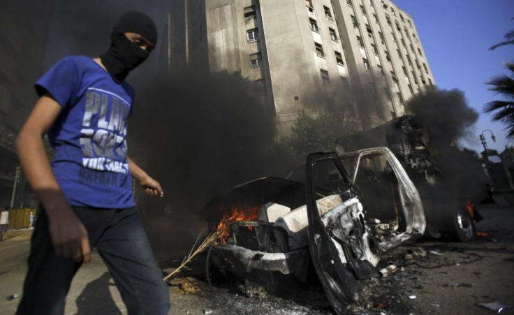 A protester walks after he set fire to a police vehicle during clashes with riot police along a road which leads to the U.S. embassy, in Cairo