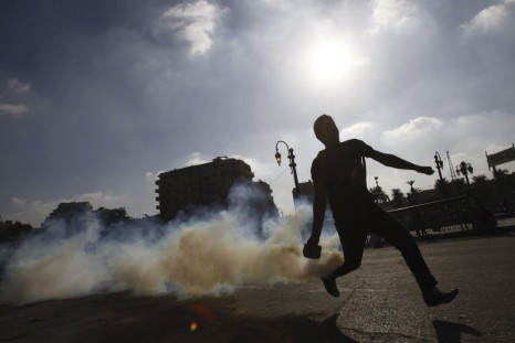 A protester throws a tear gas canister, which was earlier thrown by riot police, during clashes along a road which leads to the U.S. embassy, in Cairo