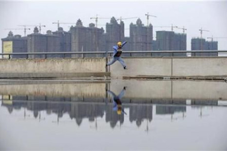 A worker jumps over a puddle near a residential construction site in Taiyuan, Shanxi province