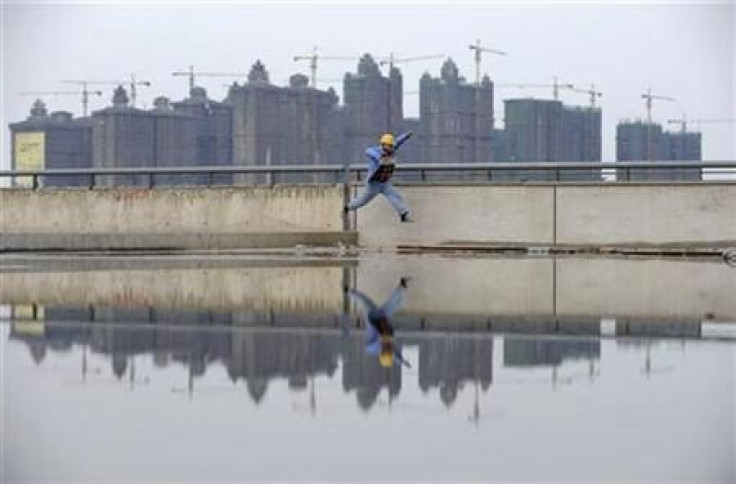 A worker jumps over a puddle near a residential construction site in Taiyuan, Shanxi province