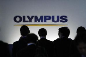 People walk past a sign of Olympus Corp outside the company&#039;s showroom in Tokyo