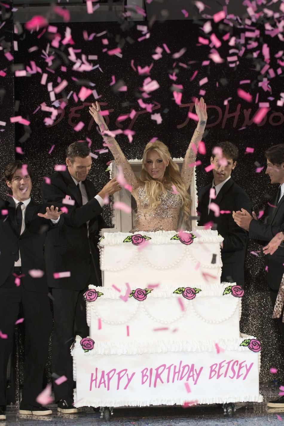 Lulu Johnson, the daughter of fashion designer Betsey Johnson, pops out of a mock-up of a cake for her mother at Betsey Johnsons retrospective fashion show and 70th birthday party during New York Fashion Week September 11, 2012. 