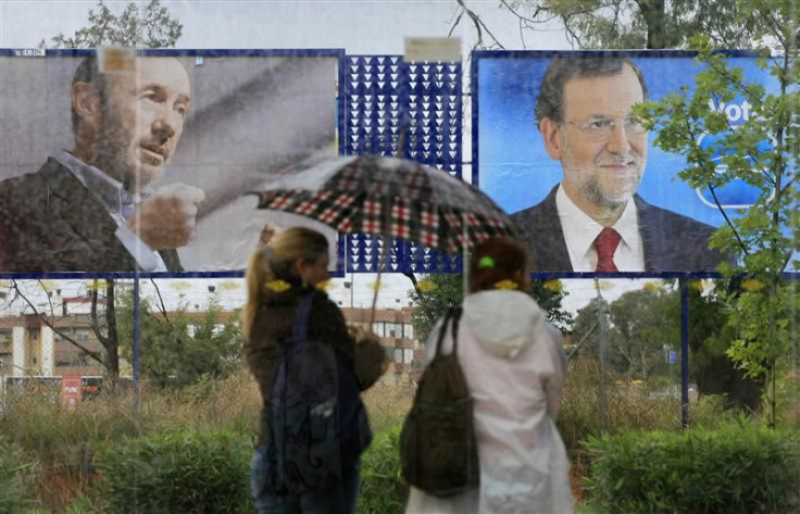 People wait in front of electoral posters at a bus stop in Seville