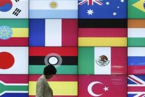 A woman walks by a signboard showing flags of the participating countries for the upcoming G20 Seoul Summit at venue of the summit in Seoul