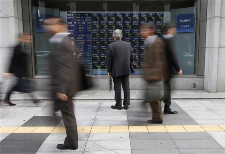 Man looks at an electronic board displaying stock prices outside a brokerage in Tokyo
