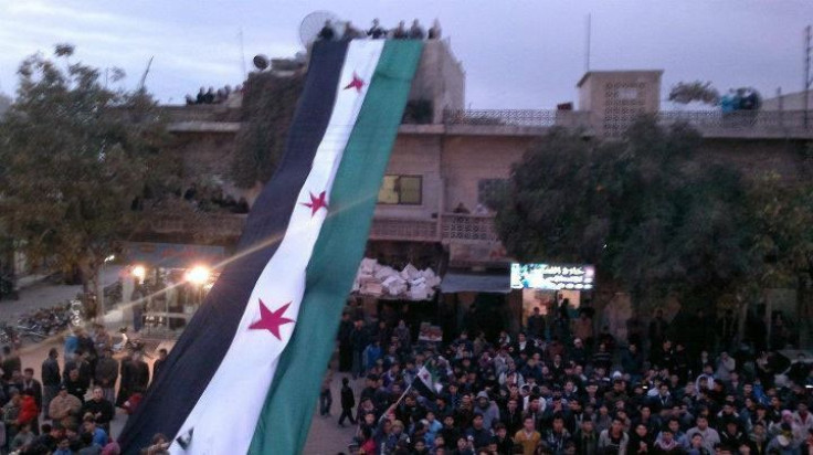 Demonstrators against Syria's President Bashar al-Assad display a large 1961-63 Syrian flag during a march after Friday prayers in Kafranbel near Adlb