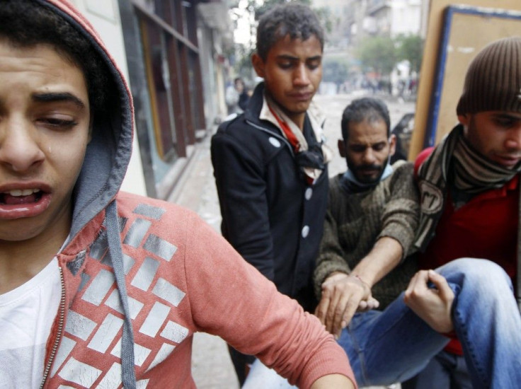 Protesters carry a man injured during clashes with riot police in a side street near Tahrir Square in Cairo