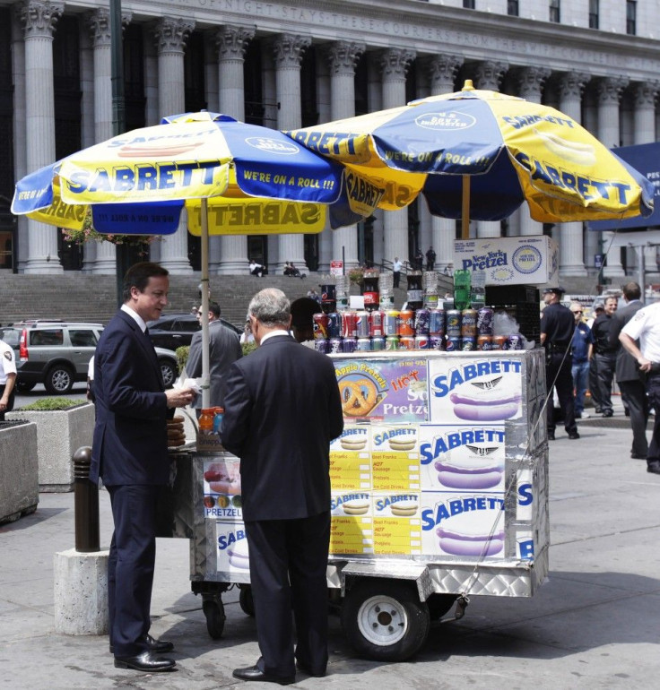 British PM David Cameron buys a hot dog with New York City Mayor Michael Bloomberg outside Penn Station in New York