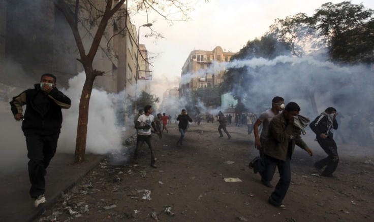 Protesters flee from tear gas fired by riot police during clashes along a road near Tahrir Square