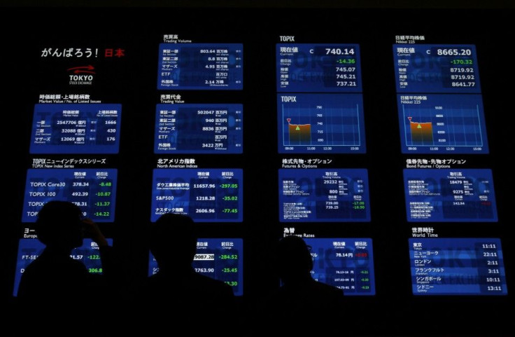 Visitors to the Tokyo Stock Exchange look at a monitor displaying various market indices in Tokyo