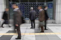 Man looks at an electronic board displaying stock prices outside a brokerage in Tokyo