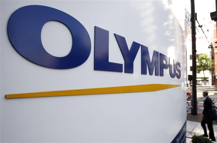 A man walks past a sign of Olympus Corp outside the company&#039;s showroom in Tokyo