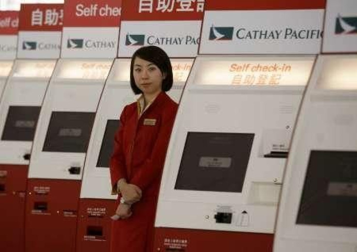 A Cathay Pacific attendant waits for customers beside a column of self check-in machines at the Hong Kong airport.