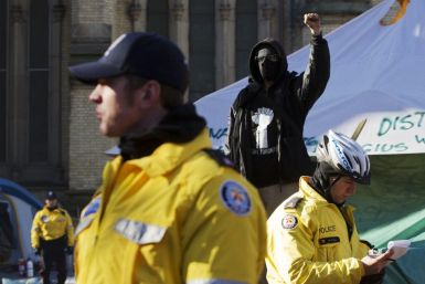 A protester raises his fist behind police officers after they moved in to evict protesters at St. James park during the &quot;Occupy Toronto&quot; movement