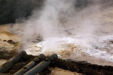 Pipes coming from a rare earth smelting plant spew polluted water into a vast tailings dam near Xinguang Village