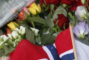 A Norwegian national flag is seen among flowers to mourn the victims of a shooting spree on an island in the countryside and a bomb attack in the capital Oslo