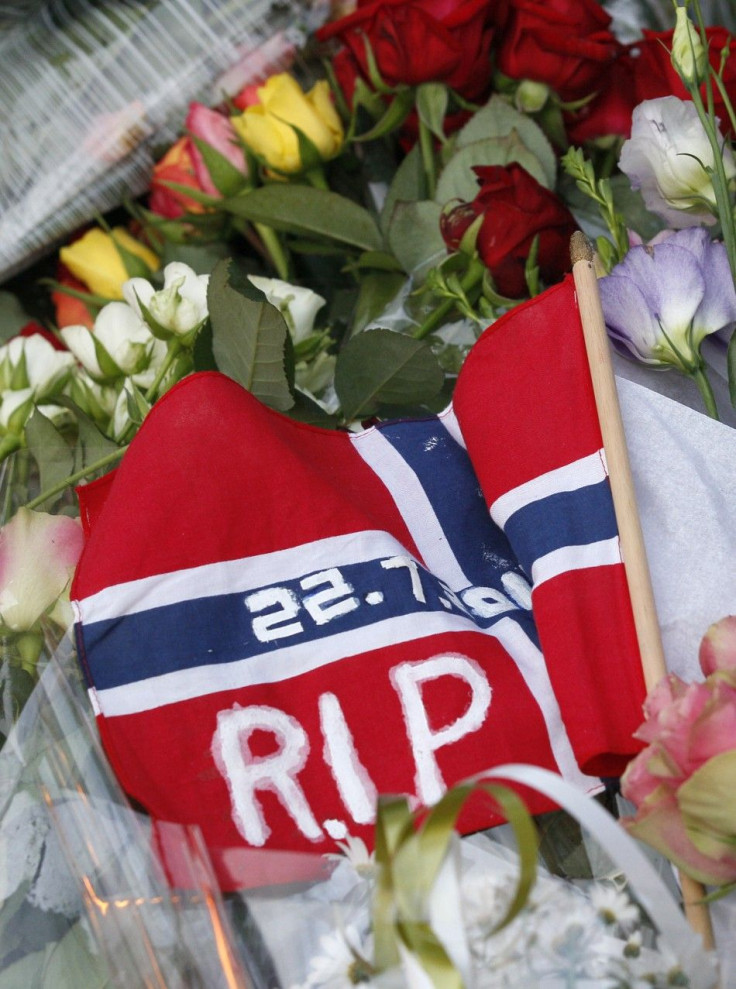 A Norwegian national flag is seen among flowers to mourn the victims of a shooting spree on an island in the countryside and a bomb attack in the capital Oslo