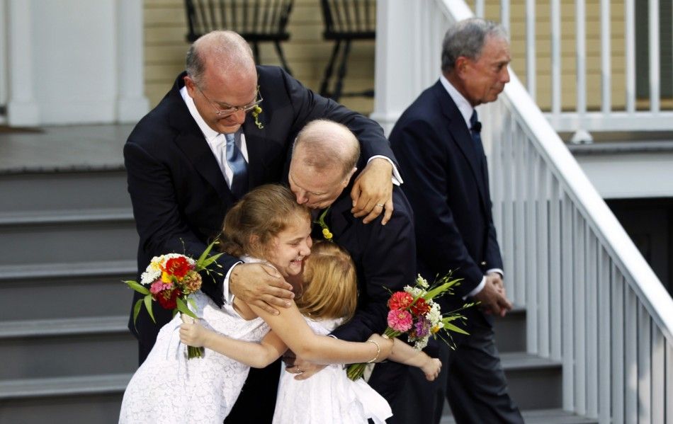 New York City Mayor Michael Bloomberg R walks away after presiding over the wedding of Jonathan Mintz L, the citys consumer affairs commissioner, and John Feinblatt C, a chief adviser to the mayor, as the newlyweds embrace their daughters Maeve 2n