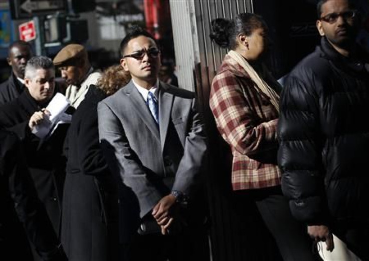 A man in sunglasses (C) looks on as he waits in line with other people to enter the NYCHires Job Fair in New York.