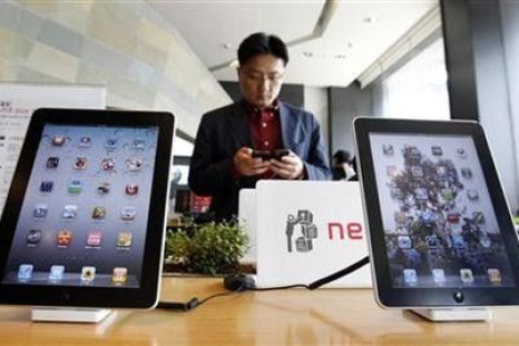 A customer holds a Apple Inc iPhone 4 smartphone on display behind the company's iPad tablets at a registration desk at the headquarters of South Korean mobile carrier KT in Seoul April 19, 2011.