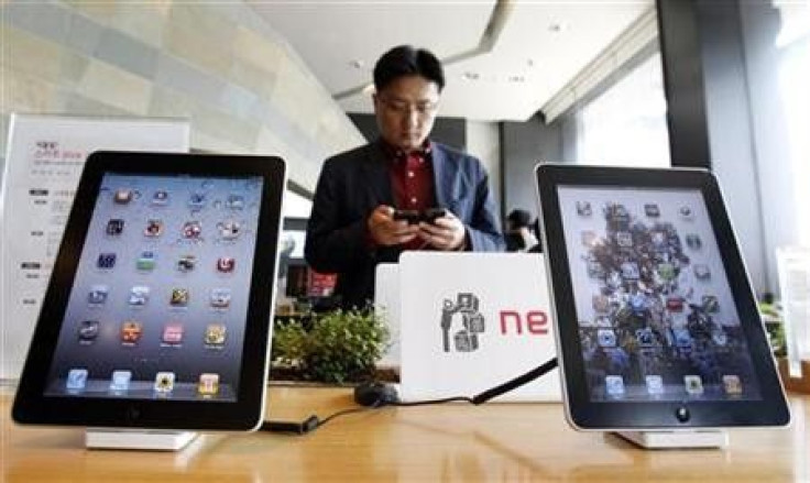 A customer holds a Apple Inc iPhone 4 smartphone on display behind the company's iPad tablets at a registration desk at the headquarters of South Korean mobile carrier KT in Seoul April 19, 2011.