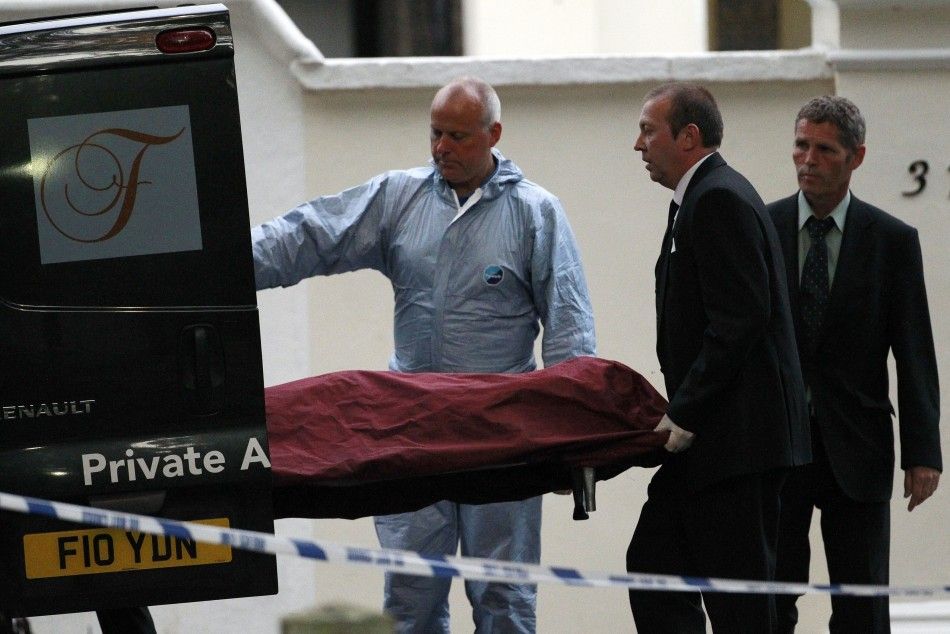 Funeral workers and apolice officer bring the body of Amy Winehouse to a van outside her house in London