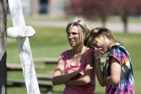 Alyssa Nikolas and Kailey Bucher read messages written to victims of the 1999 shooting at Columbine High School in Clement Park in Littleton