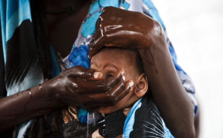 A newly arrived Somali refugee washes her child as they await medical examinations at the Dadaab refugee camp, near the Kenya-Somalia border