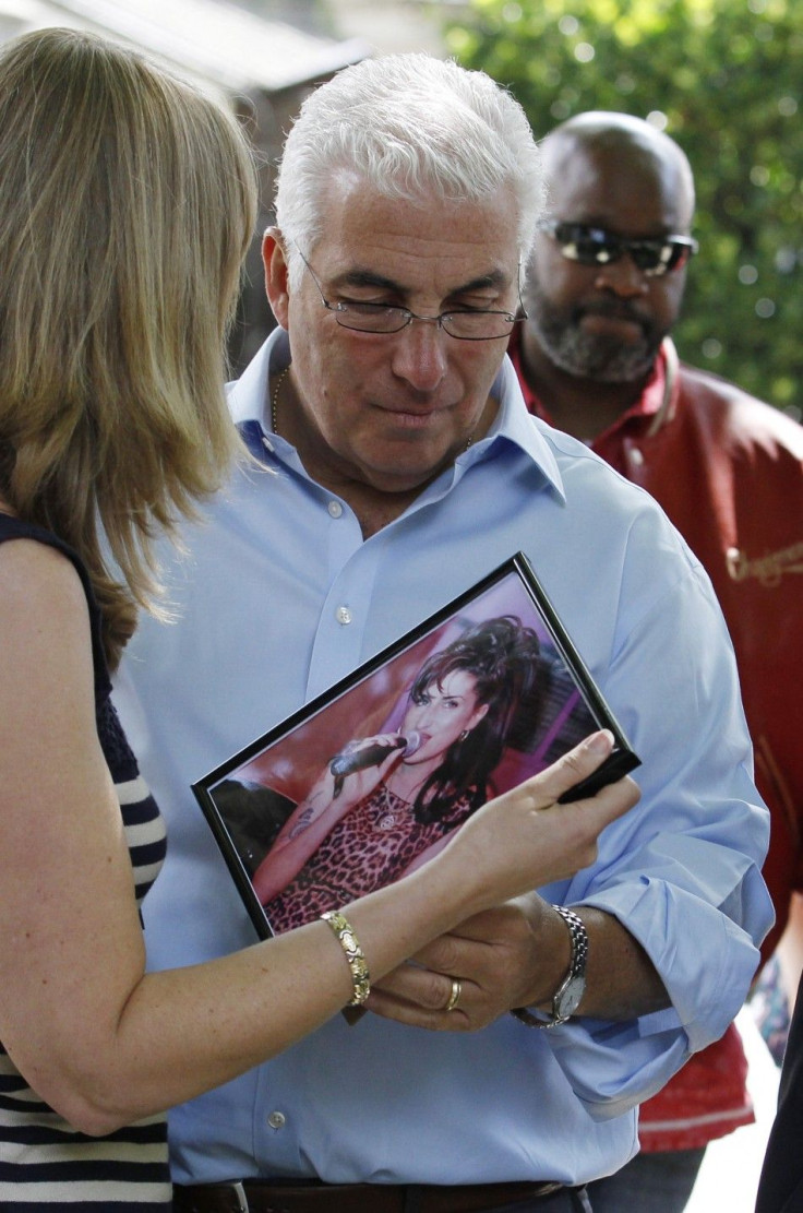 Mitch Winehouse, the father of British singer Amy Winehouse, looks at memorabilia left by fans outside her house in London