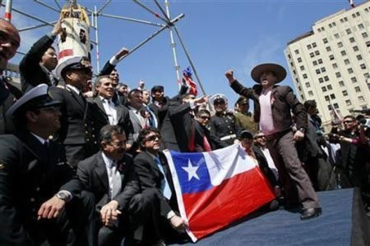 The Chilean rescued miners and members of their rescue team pose in front of the Phoenix 2 capsule that was used in the rescue of the 33 trapped miners at La Moneda government palace in Santiago