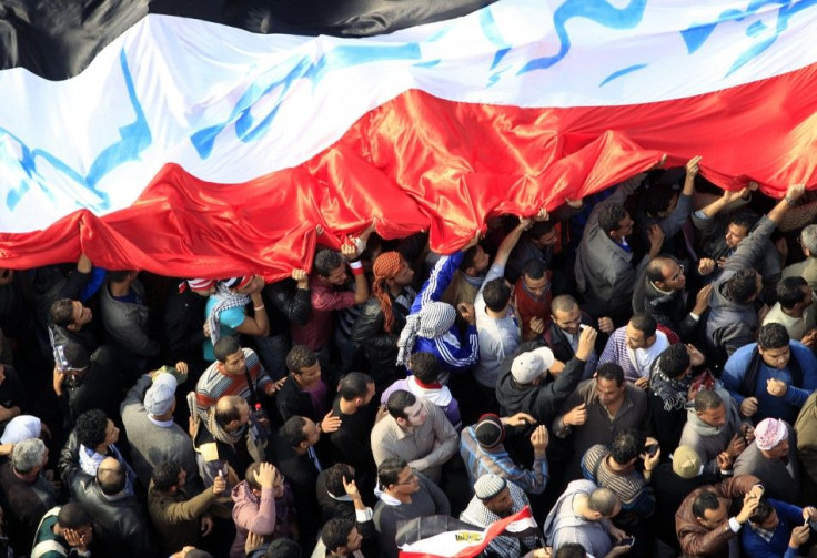 Egyptian protesters march with a huge flag during a rally at Tahrir Square in Cairo