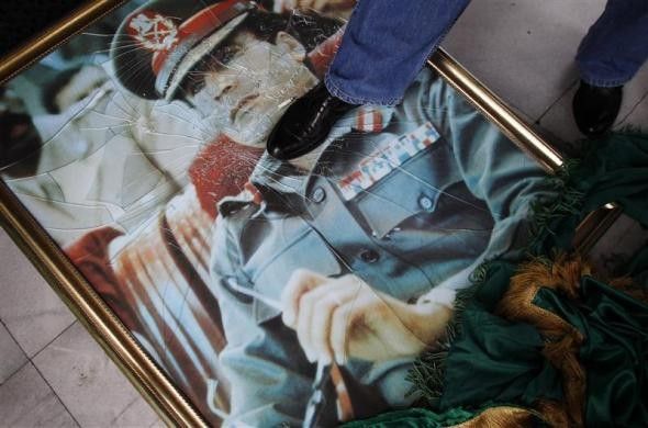 A staff member of the Libyan embassy steps on a portrait of Muammar Gaddafi