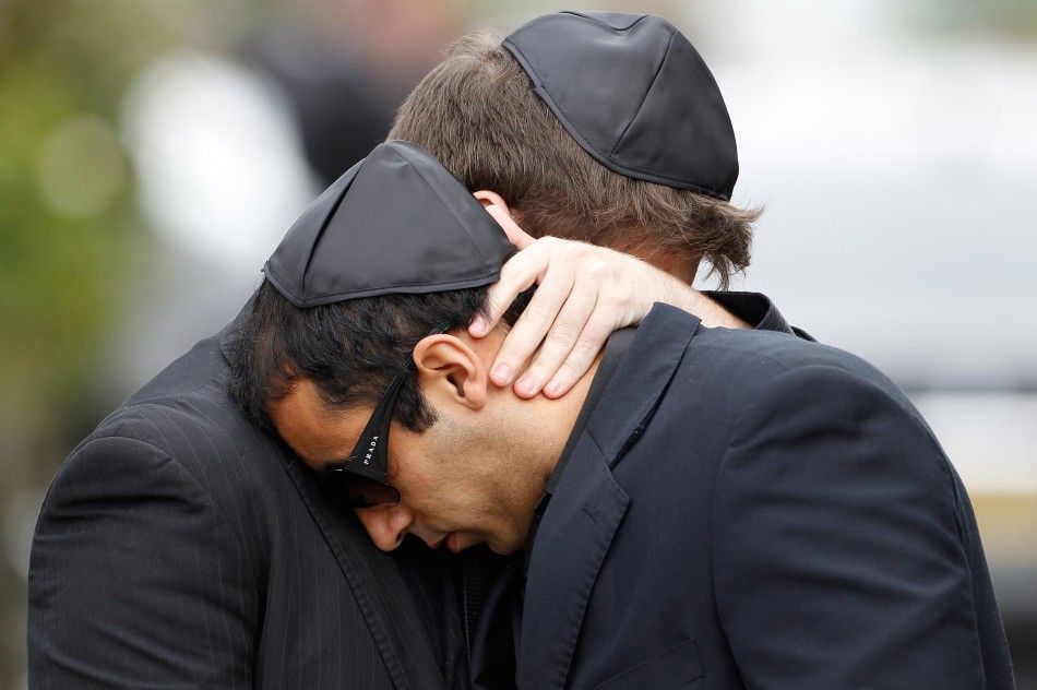 Mourners embrace as they leave the funeral service for Amy Winehouse at a cemetery in north London