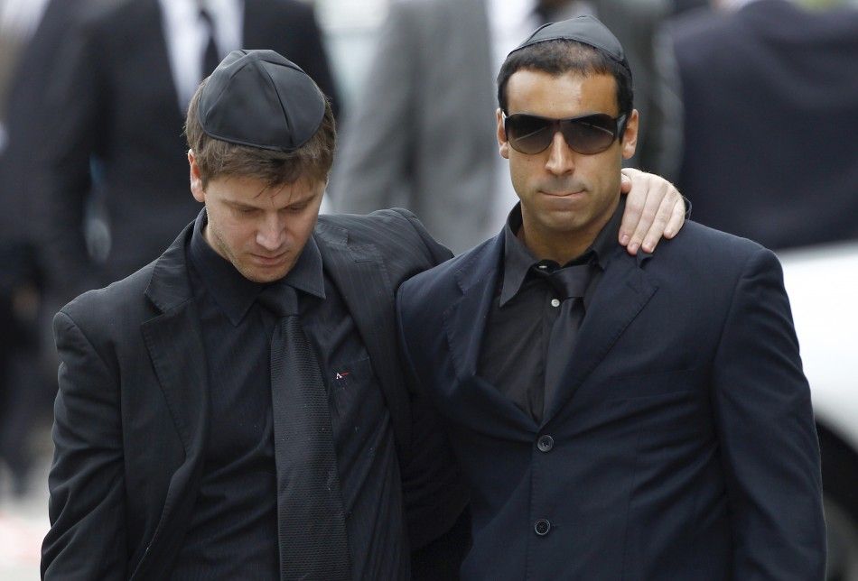 Mourners embrace as they leave the funeral service for Amy Winehouse at a cemetery in north London 