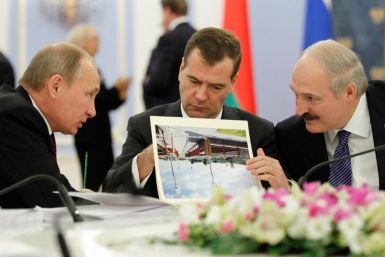 Russian PM Putin talks to Belarus&#039; President Lukashenko as Russia&#039;s President Medvedev reads document during a meeting in the Gorki residence outside Moscow