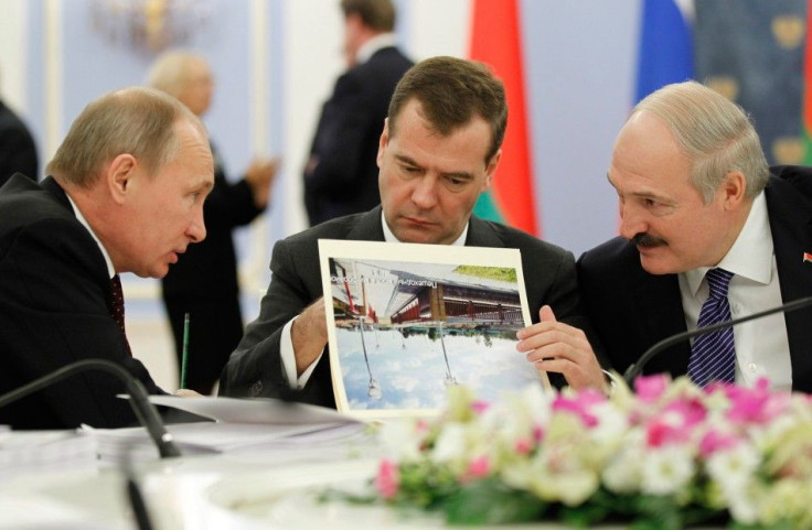 Russian PM Putin talks to Belarus&#039; President Lukashenko as Russia&#039;s President Medvedev reads document during a meeting in the Gorki residence outside Moscow