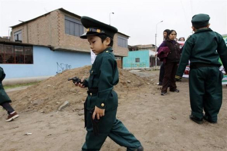A boy dressed as a police officer plays with a toy gun
