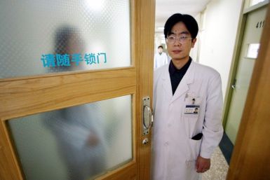 A Chinese doctor stands by the doorway as he is surrounded by patients suffering psychiatric problem..
