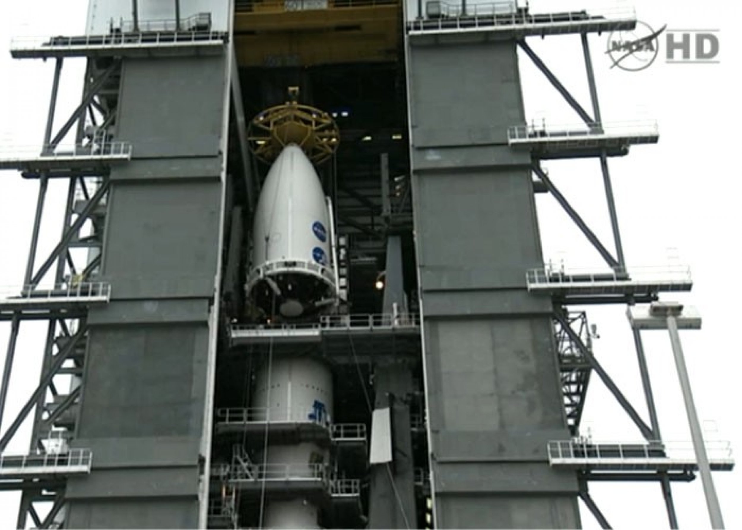 Jupiter probe Juno, which rests inside a part of Atlas V rocket, is being hoisted up the launch pad